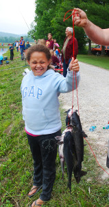 Haleigh Carpertner, of Bath County, had to have a little help to lift her heavy string of fish, which she caught Saturday morning at the derby. (Photo by Chris Erwin)